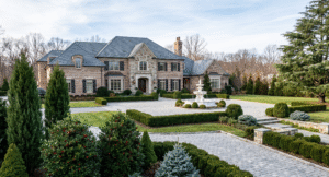 Formal estate landscaping featuring structured evergreen architecture, meticulously pruned boxwood hedges, and specimen conifers surrounding a grand stone mansion and marble fountain in a winter landscape.